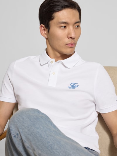 Männermodel trägt Regular Fit Poloshirt aus reiner Baumwolle von Tommy Hilfiger in Weiß mit Logo-Stitching, Nahaufnahme Oberkörper.