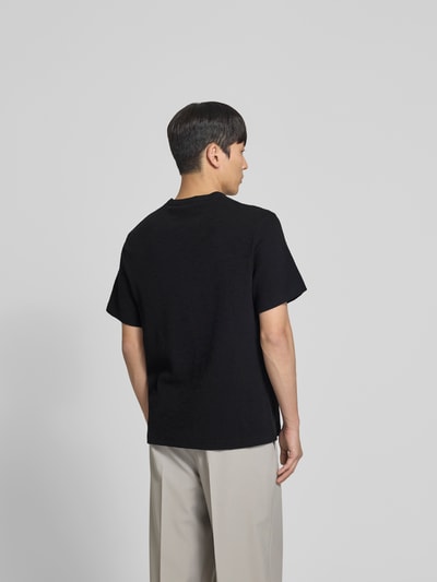 Männermodel trägt Relaxed Fit T-Shirt mit Strukturmuster von Forét in Schwarz aus Reine Baumwolle mit Logo-Stitching, Rückenlänge 69 cm, Ganzkörperansicht Rückansicht.