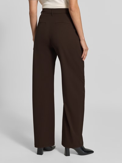 Vrouwenmodel draagt Barrel Fit stoffen broek met viscosemix van DRYKORN in donkerbruin, met strookzakken, knoop- en ritssluiting, elastische materiaalmix, bandwijdte maat 27/34: 37 cm, binnenbeenlengte 80 cm, geheel zicht van achteren.