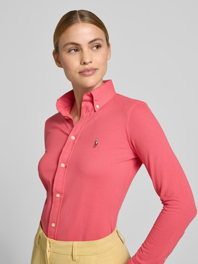 Frauenmodel trägt Regular Fit Hemdbluse aus reiner Baumwolle von Polo Ralph Lauren in Unifarbe Pink mit Logo-Stitching und Hemdkragen, Nahaufnahme Oberkörper.