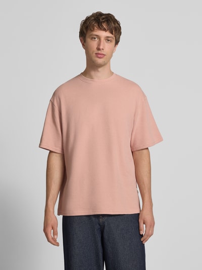 Männermodel trägt Herren T-Shirt mit Strukturmuster und Rundhalsausschnitt Modell 'PETER' von Redefined Rebel aus Baumwoll-Mix in Rosa, Relaxed-Fit, Rückenlänge bei Größe M: 70 cm, Ganzkörperansicht von vorne.
