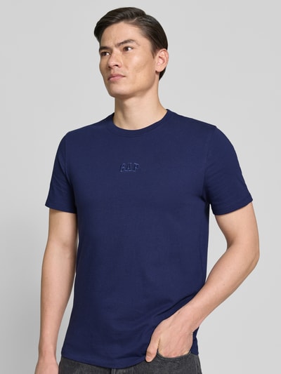Männermodel trägt T-Shirt mit Rundhalsausschnitt und Label-Stitching von GAP in Dunkelblau, Reine Baumwolle, Regular-Fit, Ganzkörperansicht von vorne.