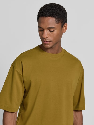 Męski model nosi Relaxed Fit T-Shirt mit Rundhalsausschnitt von JAKE*S STUDIO MEN z bawełny, krótki rękaw, kolor musztardowy, półzbliżenie na górną część ciała.