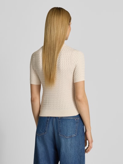 Frauenmodel trägt Slim Fit T-Shirt aus reiner Baumwolle von Tommy Hilfiger in Beige mit Zopfmuster und Logo-Detail, Stricktextur, Ganzkörperansicht Rückansicht