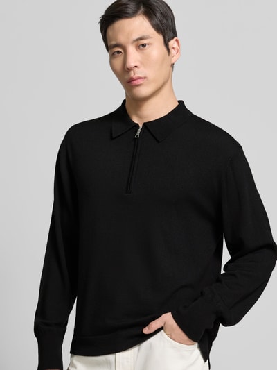 Männermodel trägt Pullover aus reiner Lanawolle von Officine Générale in Schwarz mit Polokragen und Reißverschluss, Nahaufnahme Oberkörper.