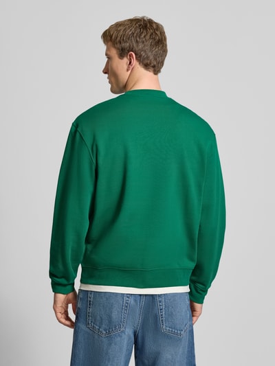 Männermodel trägt Sweatshirt mit Rundhalsausschnitt und Logo von Calvin Klein Jeans in Grün, Baumwolle, Regular-Fit, Rückenlänge 67 cm, Ganzkörperansicht Rückansicht.