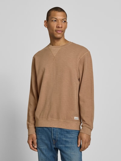 Mannenmodel draagt Regular Fit Sweatshirt met ronde hals van Scotch & Soda, katoenmix, labeldetail, ruglengte maat M 68 cm, mouwlengte 65 cm, regular fit heren sweatshirt, effen lichtbruin, textuur met fijne structuur, voorkantaanzicht, bovenlichaam close-up.