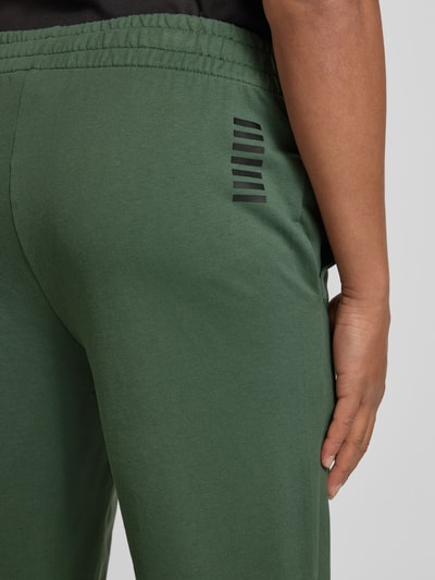 Männermodel trägt Sweatpants mit Logo und elastischem Bund von EA7 Emporio Armani, Baumwoll-Elasthan-Mix, Regular Fit, Detailaufnahme Rückansicht.