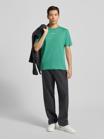Männermodel trägt Regular Fit T-Shirt aus reiner Baumwolle von Marc O'Polo in Optik: Unifarben mit Label-Print, Ganzkörperansicht von vorne.