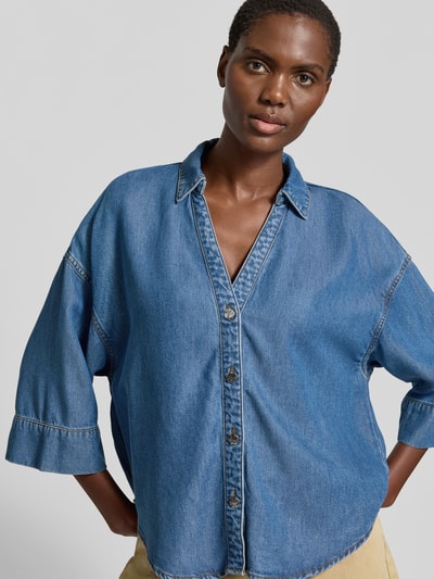 Vrouwenmodel draagt Boxy Fit Bluse aus Lyocell Modell 'Milo' van FREE/QUENT, denim-look, V-hals, blauwe tint, lyocelltextuur, halflange mouw, vooraanzicht bovenlichaam.