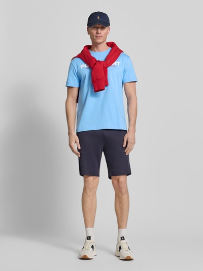 Männermodel trägt Relaxed Fit T-Shirt aus reiner Baumwolle von Polo Ralph Lauren, unifarbenes Hellblau, Label Print, Rundhals, Ganzkörperansicht von vorne.