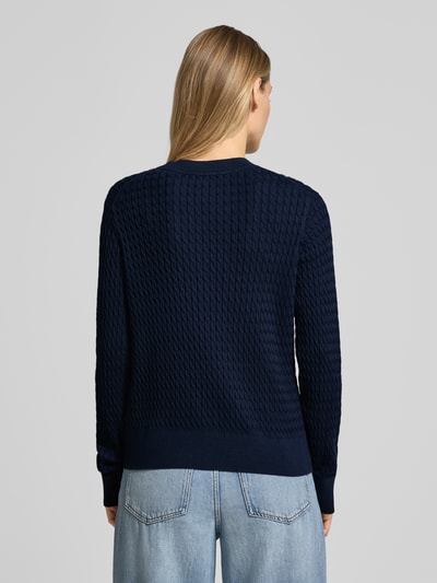 Frauenmodel trägt dunkelblauen Slim Fit Pullover aus reiner Baumwolle von Tommy Hilfiger mit Zopfmuster und gerippten Abschlüssen, Ganzkörperansicht Rückansicht.
