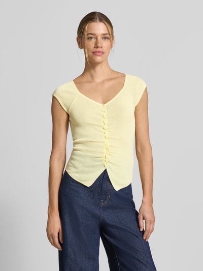 Frauenmodel trägt Strickshirt mit Knopfleiste und Raffungen von JAKE*S STUDIO WOMAN in Gelb, Viskose-Mix, Körpernaher-Schnitt, V-Ausschnitt, Ganzkörperansicht von vorne.