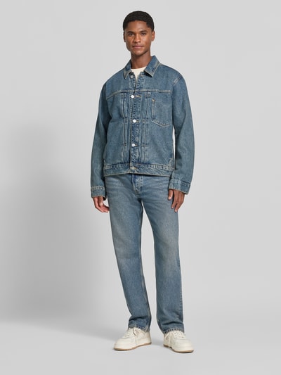 Männermodel trägt Regular Fit Jeansjacke aus Baumwoll-Lyocell-Mix Modell 'AASHTON' von ARMEDANGELS in Blau, Ganzkörperansicht von vorne, Herren Jeansjacke.