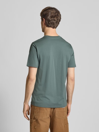 Männermodel trägt Regular Fit T-Shirt mit Logo-Patch von Carhartt Work In Progress aus reiner Baumwolle, Grün, Ganzkörperansicht Rückansicht.