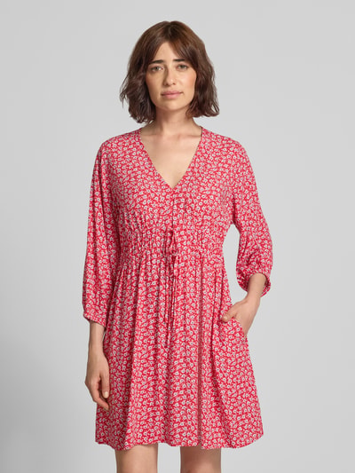 Frauenmodel trägt Minikleid aus reiner Viskose mit floralem Allover-Print von GAP in Rot mit weißem Muster, V-Ausschnitt, 3/4-Arm, taillierte Passform, leichte Textur, Nahaufnahme Oberkörper.