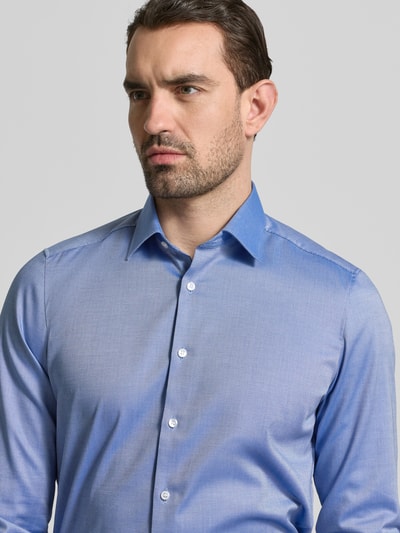 Männermodel trägt Slim Fit Business-Hemd mit Strukturmuster und Kentkragen von OLYMP Level Five, blauer Baumwoll-Mix, Nahaufnahme Oberkörper.