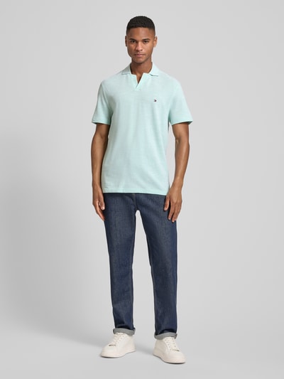 Männermodel trägt Regular Fit Poloshirt aus reiner Baumwolle von Tommy Hilfiger in Melange-Optik, Logo-Stitching, Ganzkörperansicht von vorne.