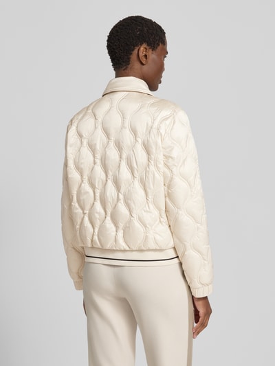 Frauenmodel trägt Steppjacke mit Umlegekragen und Reißverschlusstaschen von Marc Cain in Creme, glatte Oberfläche, Rückenlänge 56 cm, Ganzkörperansicht Rückansicht.