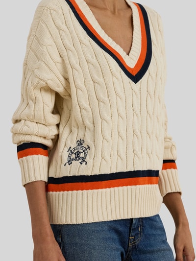Frauenmodel trägt Regular Fit Strickpullover aus reiner Baumwolle von Lauren Ralph Lauren, Optik: Unifarben, Zopfmuster, Logo-Detail, Kontraststreifen, V-Ausschnitt, Langarm, Ärmelabschluss und Rumpfabschluss gerippt, Strick, Nahaufnahme Oberkörper.