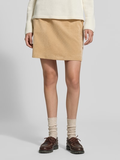 Frauenmodel trägt Regular Fit Mini-Rock in Cord-Optik von OPUS in Beige mit glatter Textur, kombiniert mit heller Strickmode, Nahaufnahme Oberkörper. Damen Mini-Rock von OPUS.