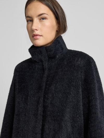 Vrouwenmodel draagt Jacke mit Kunstfell van comma in zwart, losse pasvorm, staande kraag, elastische mouwen, materiaal-mix. Nahaufnahme bovenlichaam.