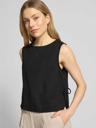 Frauenmodel trägt Blusenshirt mit seitlicher Schnürung Modell 'Svetlana' von Neo Noir, schwarze Reine Baumwolle, lockerer Schnitt, Rundhalsausschnitt, Rückenlänge bei Größe 36 51 cm, Nahaufnahme Oberkörper.