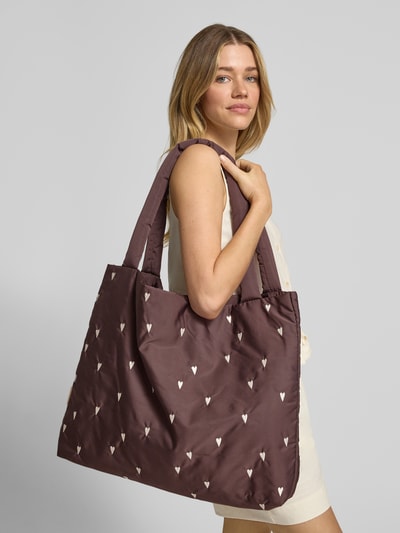 Frauenmodel trägt Handtasche mit Allover-Motiv-Stitching Modell 'Mom' von STUDIO NOOS in Braun mit weißen Motiven, Hauptfach, Schulterriemen, Ganzkörperansicht von vorne. Breite 55 cm, Länge 47 cm, Tiefe 8 cm, Länge Schulterriemen 73 cm, Damen Handtasche.