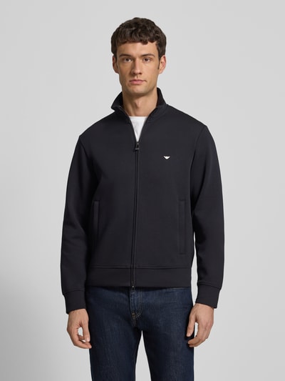 Männermodel trägt Regular Fit Sweatjacke mit Logo-Stitching von Emporio Armani, Baumwoll-Mix, Stehkragen, Zweiwege-Reißverschluss, Eingrifftaschen, elastische Abschlüsse, dunkelblau, Ganzkörperansicht von vorne.