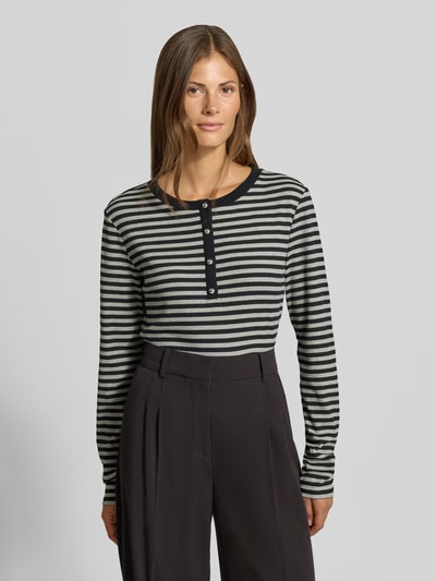 Frauenmodel trägt Longsleeve mit Henley-Kragen von MYON, Streifenmuster, tailliert, Rippstruktur, Baumwoll-Elasthan-Mix, Ganzkörperansicht von vorne.