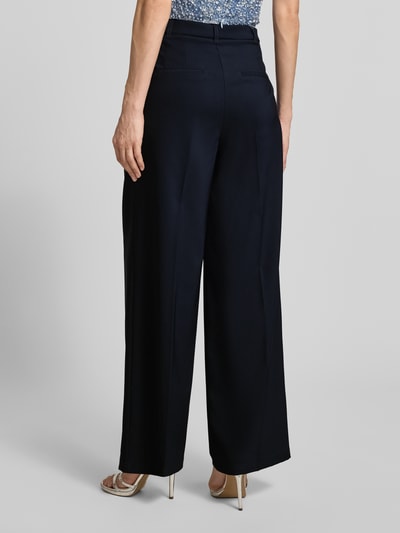 Männermodel trägt Wide Leg Hose mit Bindegürtel von Betty Barclay, ciemnogranatowy materiał z lekkim połyskiem, kanty, pasek, materiał stretch, szerokość w rozmiarze 36: 38 cm, długość wewnętrzna nogawki 78 cm, widok całej sylwetki od tyłu.