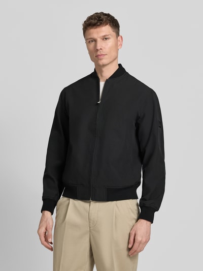 Männermodel trägt zwarte Bomberjacke met opstaande kraag model 'BLAASPEN' van Jack & Jones Premium, materiaal-mix met stretch, losse fit, rits, elastische boorden, zijzakken; vooraanzicht, bovenlichaam close-up.