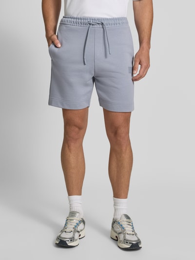 Männermodel trägt Regular Fit Sweatshorts aus Baumwoll-Mix Modell 'JT_SHORTS' von BOSS, hellgrau, glatte Struktur, Herren Sweatshorts von BOSS Green, Ganzkörperansicht von vorne.