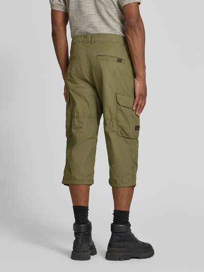 Męski model nosi Capri-Bermudas mit Cargotaschen od camel active z bawełny, krój regular fit, kieszenie cargo, detal z logo, całkowity widok z tyłu.