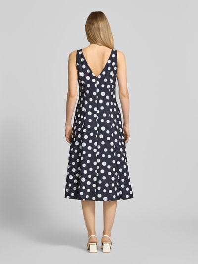 Frauenmodel trägt Cocktailkleid im Allover-Look von Vera Mont in Dunkelblau mit weißen Punkten, A-Linie, Midikleid, Material-Mix mit Stretch-Anteil, Rundhalsausschnitt, Rückenlänge bei Größe 36: 32 cm, Brustweite bei Größe 36: 36 cm, Ganzkörperansicht Rückansicht.