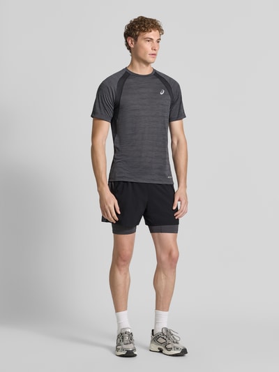 Męski model nosi Regular Fit Shorts mit integrierten Tights Model 'Road' von ASICS TIGER, krój regular fit, elastyczny pas, detal z logo, Szerokość w rozmiarze M: 38 cm, Długość wewnętrzna nogawki: 12 cm, przód, zdjęcie całopostaciowe