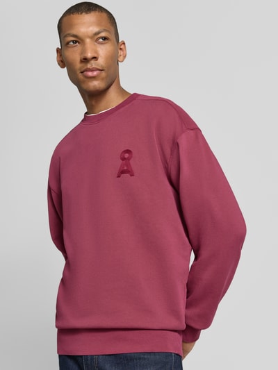 Männermodel trägt Relaxed Fit Sweatshirt aus reiner Baumwolle Modell 'ICONIC Å GMT' von ARMEDANGELS in Dunkelrot mit dezenter Struktur, Ganzkörperansicht von vorne. Herren Sweatshirt.