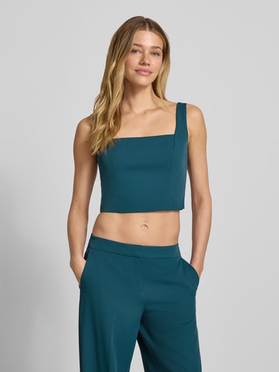 Frauenmodel trägt Cropped Top mit Karree-Ausschnitt und rückseitigem Reißverschluss von Jake*s Cocktail in Petrol, körpernah geschnitten, Material-Mix mit Stretch-Anteil, Nahaufnahme Oberkörper.