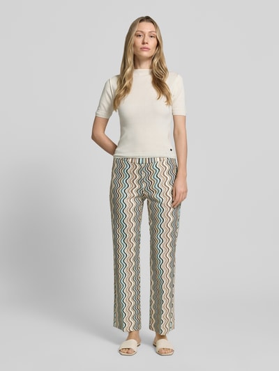 Frauenmodel trägt Hose in verkürzter Passform Modell 'FAITH' von Cambio im modernen Zickzack-Muster, Modal-Mix mit Viskose-Anteil, elastischer Bund, Bundweite bei Größe 36: 35 cm, Innenbeinlänge bei Größe 36: 78 cm, Ganzkörperansicht von vorne.