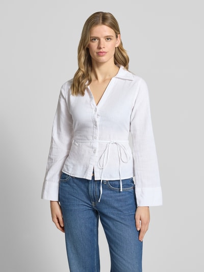 Frauenmodel trägt Leinenbluse mit Bindegürtel und V-Ausschnitt von Gina Tricot in Weiß, taillierter Schnitt, Baumwoll-Leinen-Mix, Kentkragen, Knopfleiste, Rückenlänge 60 cm, Ärmellänge 64 cm, Ganzkörperansicht von vorne.