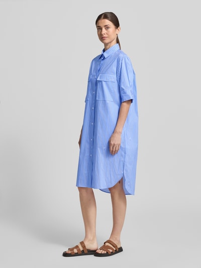 Modelka prezentuje sukienkę koszulową Relaxed Fit Hemdblusenkleid mit Brusttaschen Modell 'Daliya' od JOOP!, elastyczna mieszanka bawełny, kieszenie na piersi, rękaw o dł. 1/2, kołnierzyk koszulowy, nadruk z logo na całej powierzchni, listwa guzikowa, długość tyłu w rozmiarze 36: 108 cm, szerokość w rozmiarze 36: 52 cm, długość rękawów w rozmiarze 36: 30 cm, niebieskie paski, prosta tekstura, widok całej sylwetki z przodu.