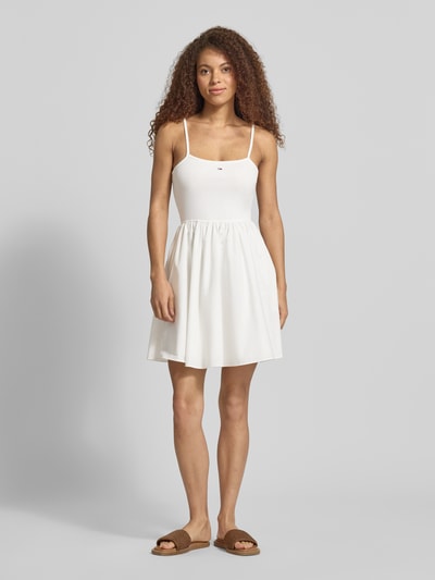 Frauenmodel trägt Tailliertes Freizeitkleid aus reiner Baumwolle von Tommy Jeans, Optik: Unifarben, Mini-Länge, Spaghettiträger, Logo-Stitching, U-Ausschnitt, seitliche Eingrifftaschen, Ganzkörperansicht von vorne.