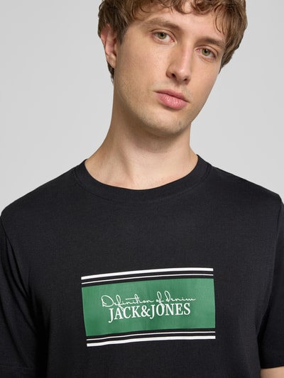 Männermodel trägt Regular Fit T-Shirt mit Logo-Print Modell 'Buster' von JACK & JONES aus Baumwolle, Nahaufnahme Oberkörper.