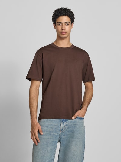 Męski model nosi Regular Fit T-Shirt mit Logo-Stitching von KARL KANI, bawełna, okrągły dekolt, długość tyłu w rozmiarze M: 64 cm, Ganzkörperansicht von vorne.