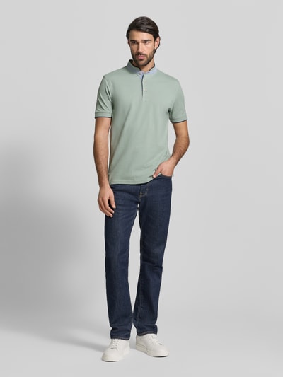 Męski model nosi Regular Fit Koszulka polo z czystej bawełny ze stójką od Christian Berg Men, jasna z gładką teksturą, krój regular fit, stójka z listwą guzikową, krótkie rękawy, elastyczne zakończenia rękawów, długość tyłu 75 cm w rozmiarze M, widok całej sylwetki z przodu.