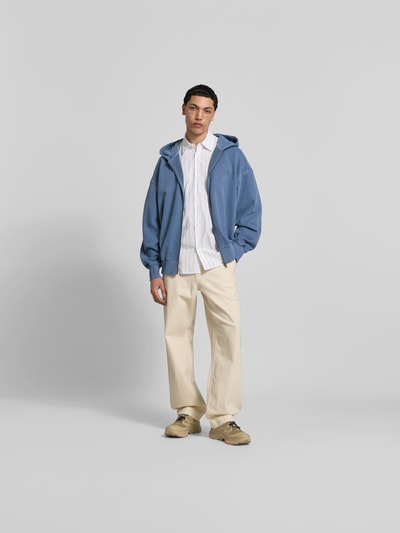 Männermodel trägt Oversized Sweatjacke aus Baumwolle von ANNARR in Blau mit Zweiwege-Reißverschluss und Balloon-Look, Ganzkörperansicht von vorne. Rückenlänge 73 cm, Schulterbreite 48 cm, Ärmellänge 74 cm, elastische Abschlüsse, Reine Baumwolle.