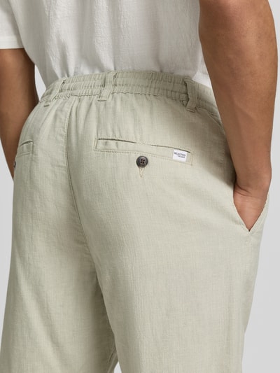 Männermodel trägt Slim Fit Hose aus Baumwoll-Leinen-Mix Modell 'BRODY' von SELECTED HOMME in Melange-Optik mit Label-Applikation, Detailaufnahme der Rückansicht.