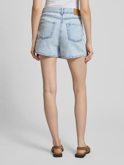 Frauenmodel trägt Skort mit Knopfverschluss Modell 'GRETA' von JJXX in Denim-Optik, Gerader-Schnitt, Reine Baumwolle, Minirock, Gesäßtasche, Bundweite 37 cm, Innenbeinlänge 34 cm, Ganzkörperansicht Rückansicht.
