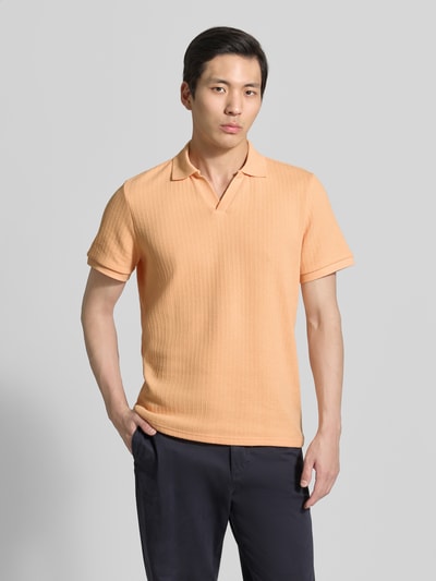 Männermodel trägt Regular Fit Strick-Poloshirt mit V-Ausschnitt von MCNEAL aus Baumwoll-Mix mit Stretch-Anteil in Apricot, Ganzkörperansicht von vorne.