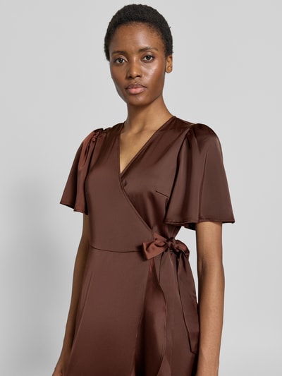 Vrouwenmodel draagt midi-jurk van elastische materiaalmix in bruin satijn met v-hals, wikkellook, korte mouwen. Model 'Thea' van YAS, borstwijdte 47 cm, ruglengte 122 cm, mouwlengte 28 cm. Nahaufnahme Oberkörper.